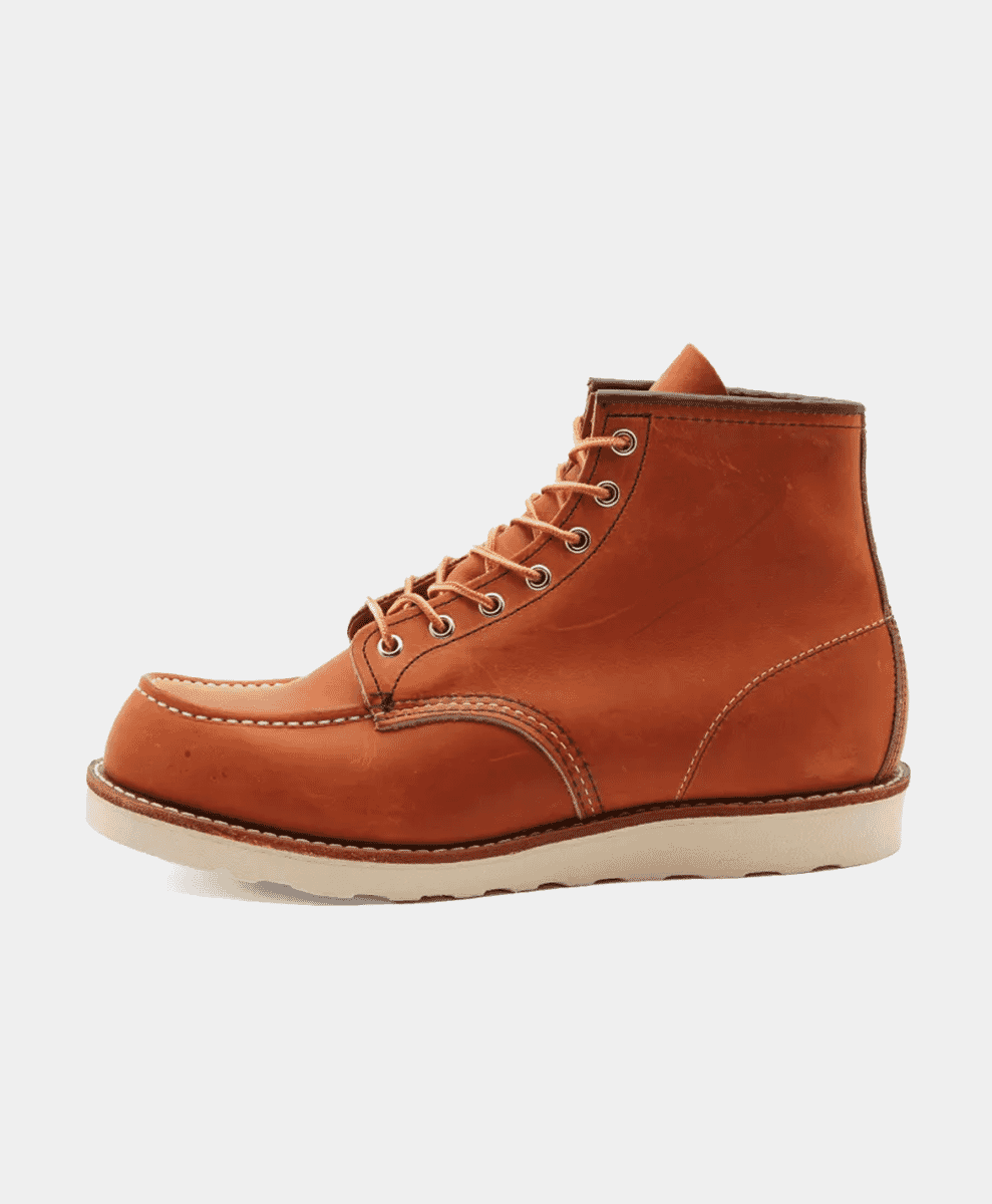 A tan leather moc-toe work boot with white stitching and a cream sole against a white background.
