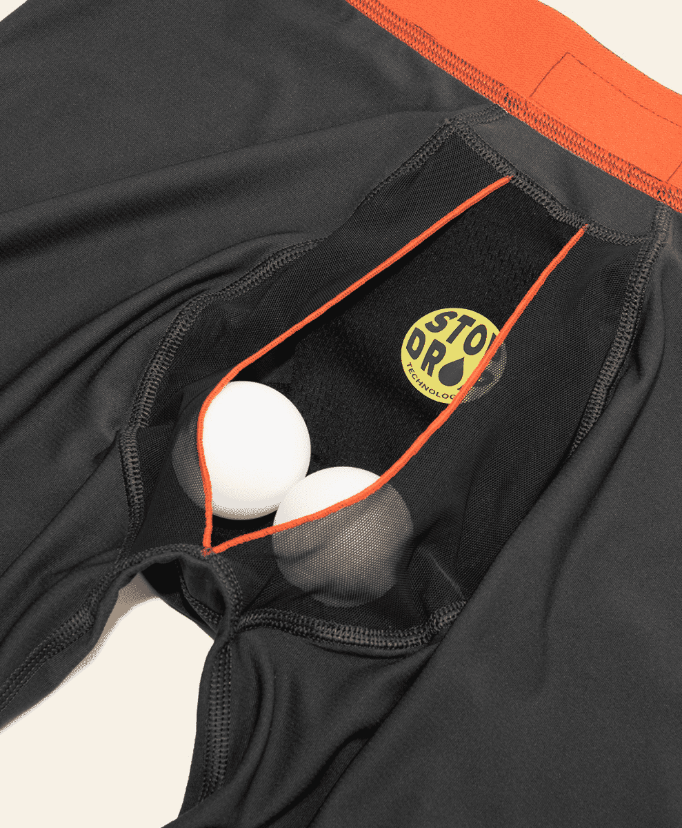 Close-up of black STODR technology athletic underwear with a mesh pouch holding two white eggs.