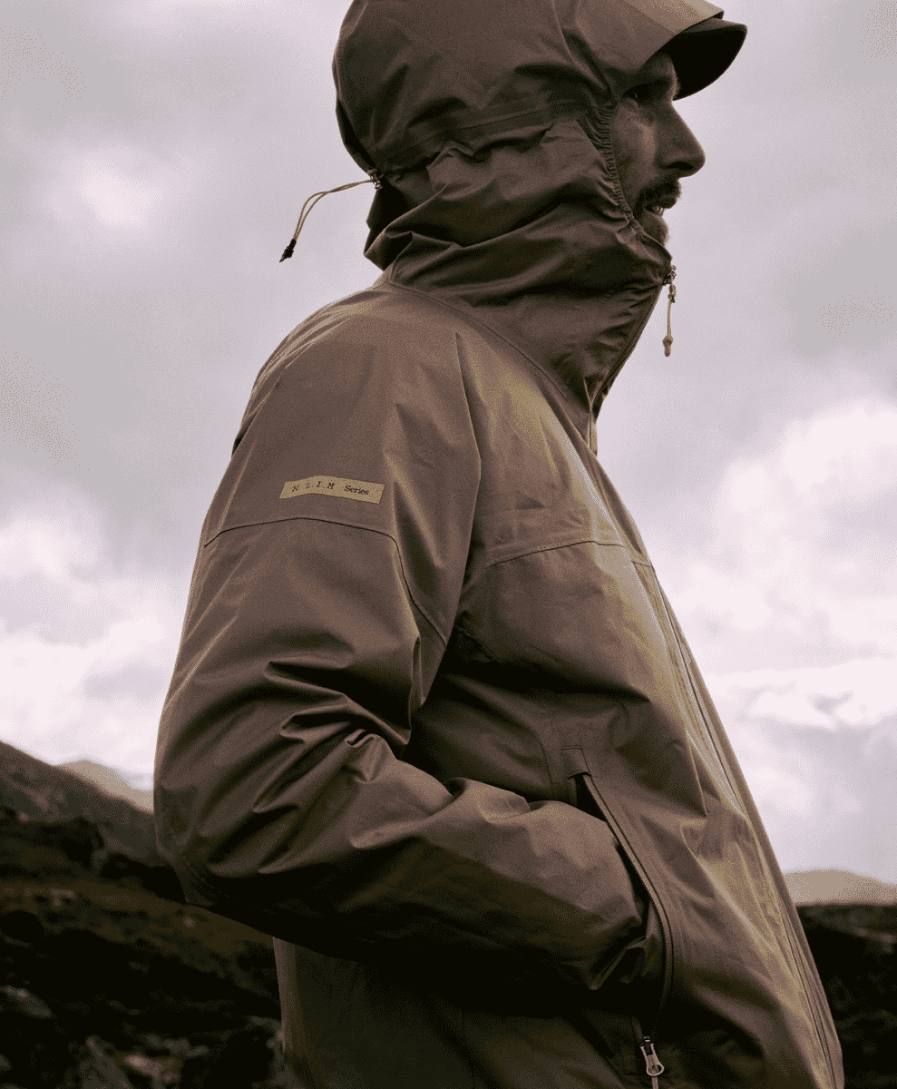Profile view of a man in a brown hooded jacket featuring the 'L.I.M Series' patch on the arm.