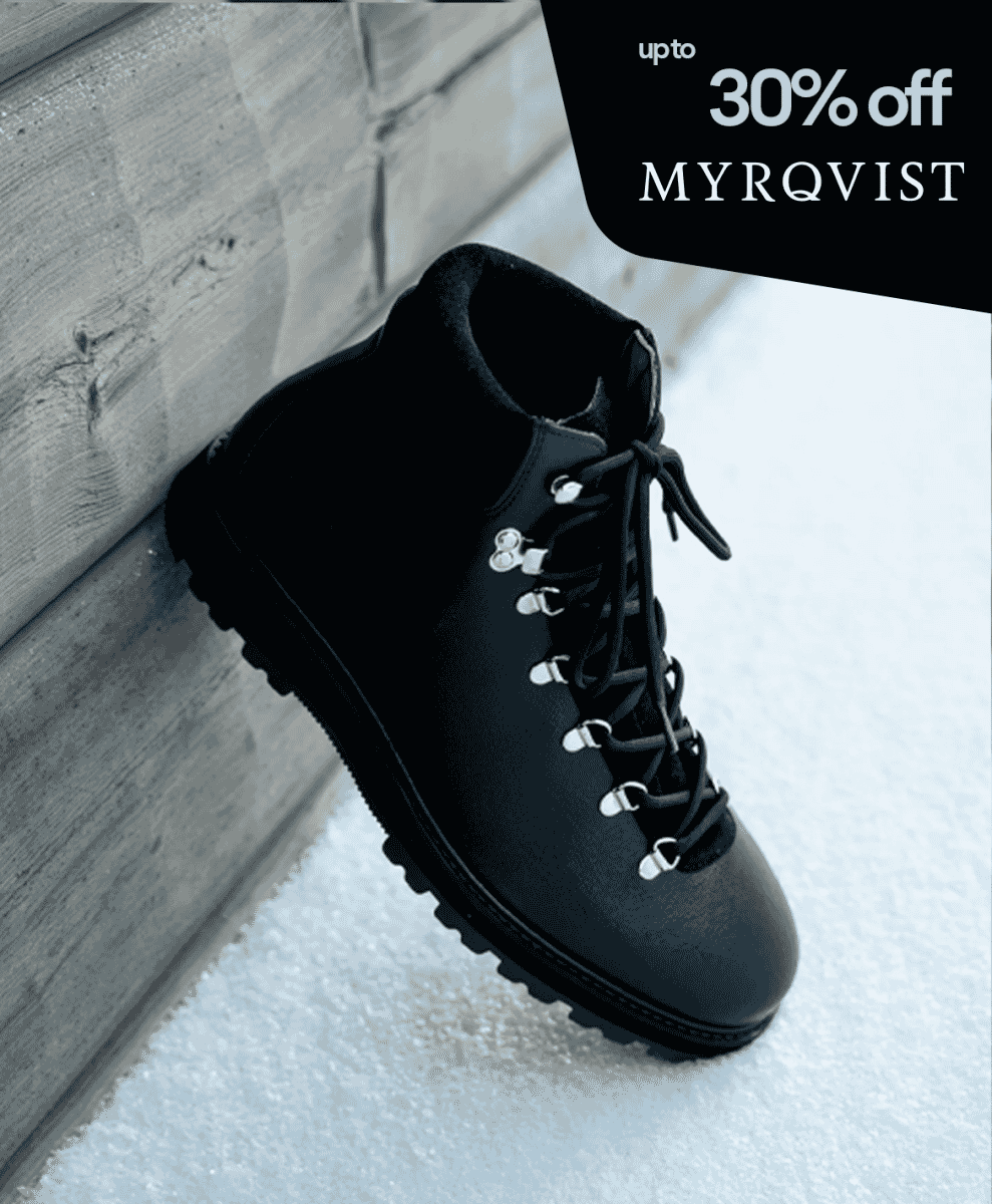 A black leather hiking boot with silver eyelets resting on snow.