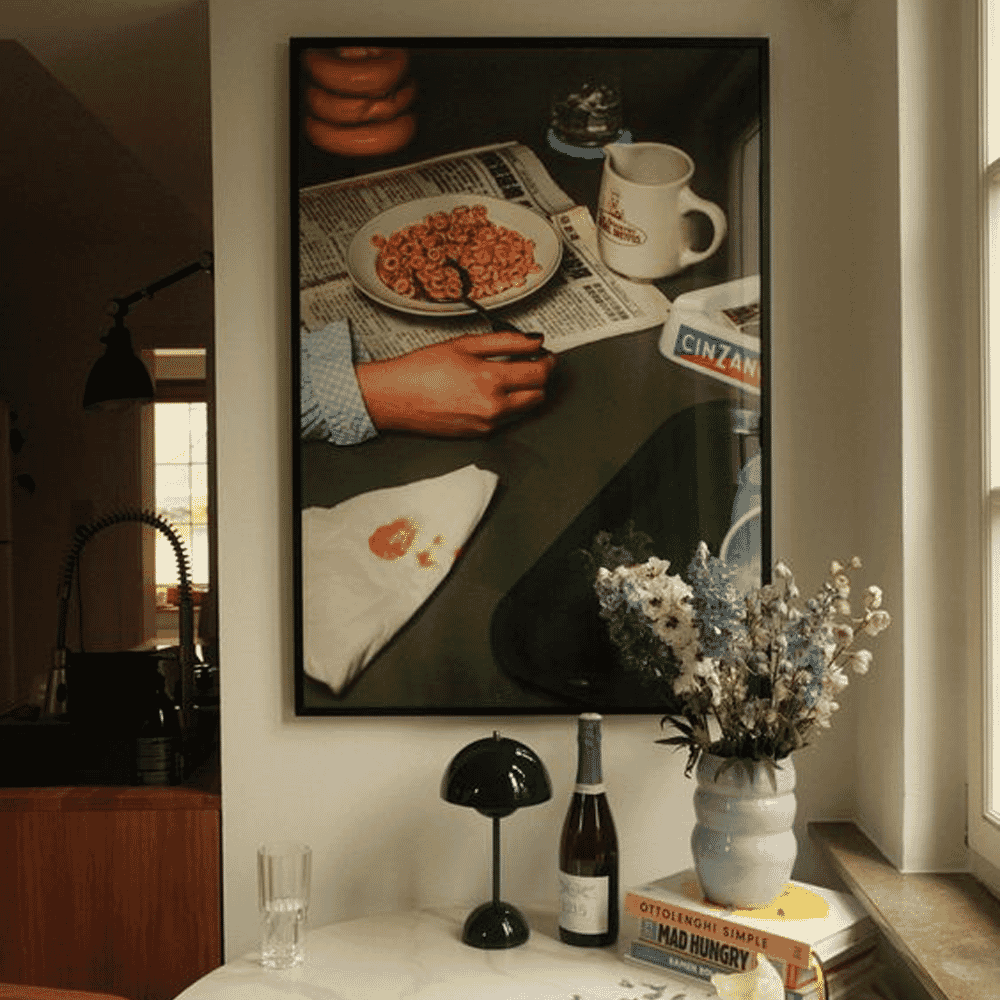 A framed painting of a person eating cereal at a table, blending vintage still life with modern interior styling.