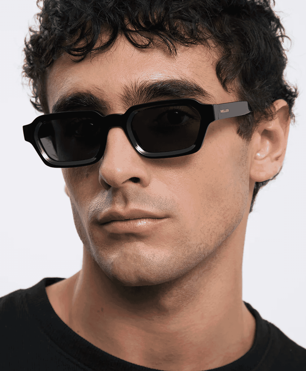 Man wearing black rectangular acetate sunglasses with side branding.