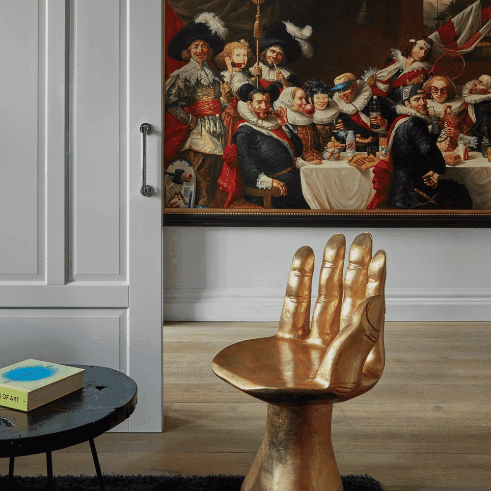 Modern interior featuring a golden hand-shaped chair and historical-themed artwork.