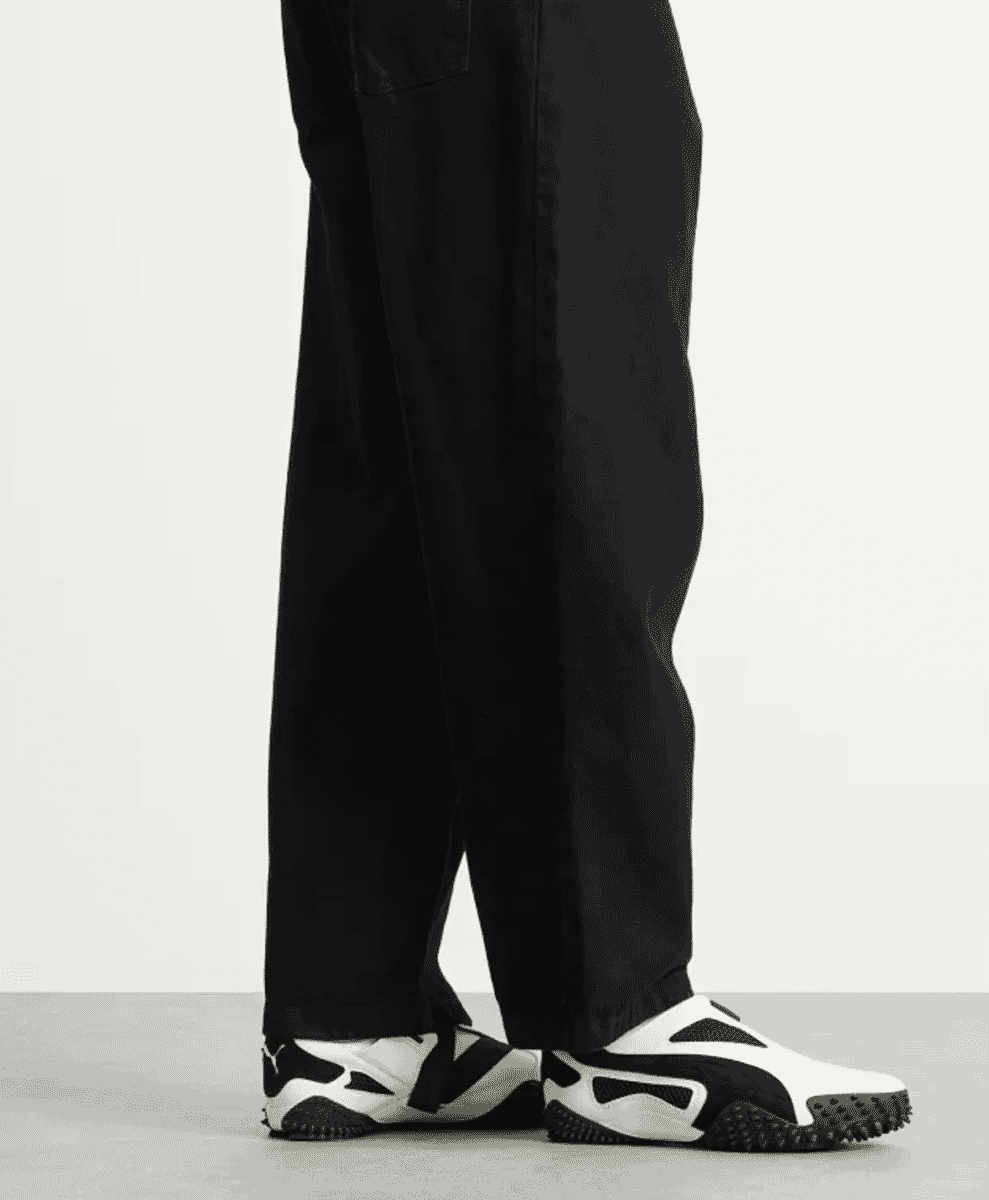 Full view of black wide-leg trousers paired with warm white Puma Ur Mostro sneakers.