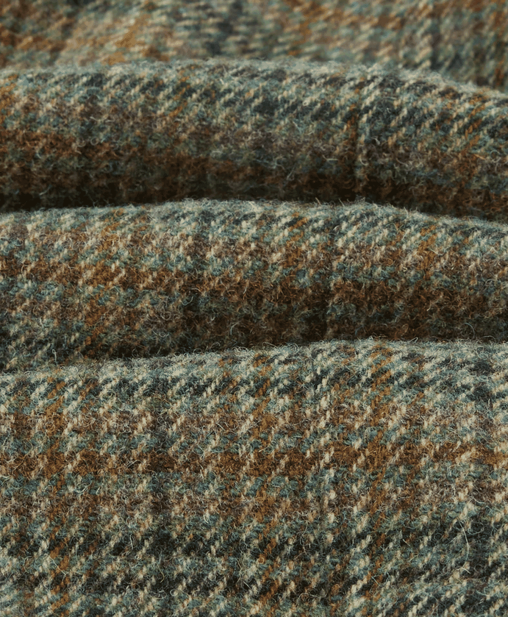 Close-up of earthy-toned tweed fabric with a classic herringbone pattern.