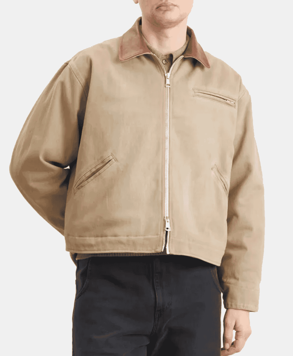 Model wearing a beige waxed cotton bomber jacket with a contrasting brown leather collar.
