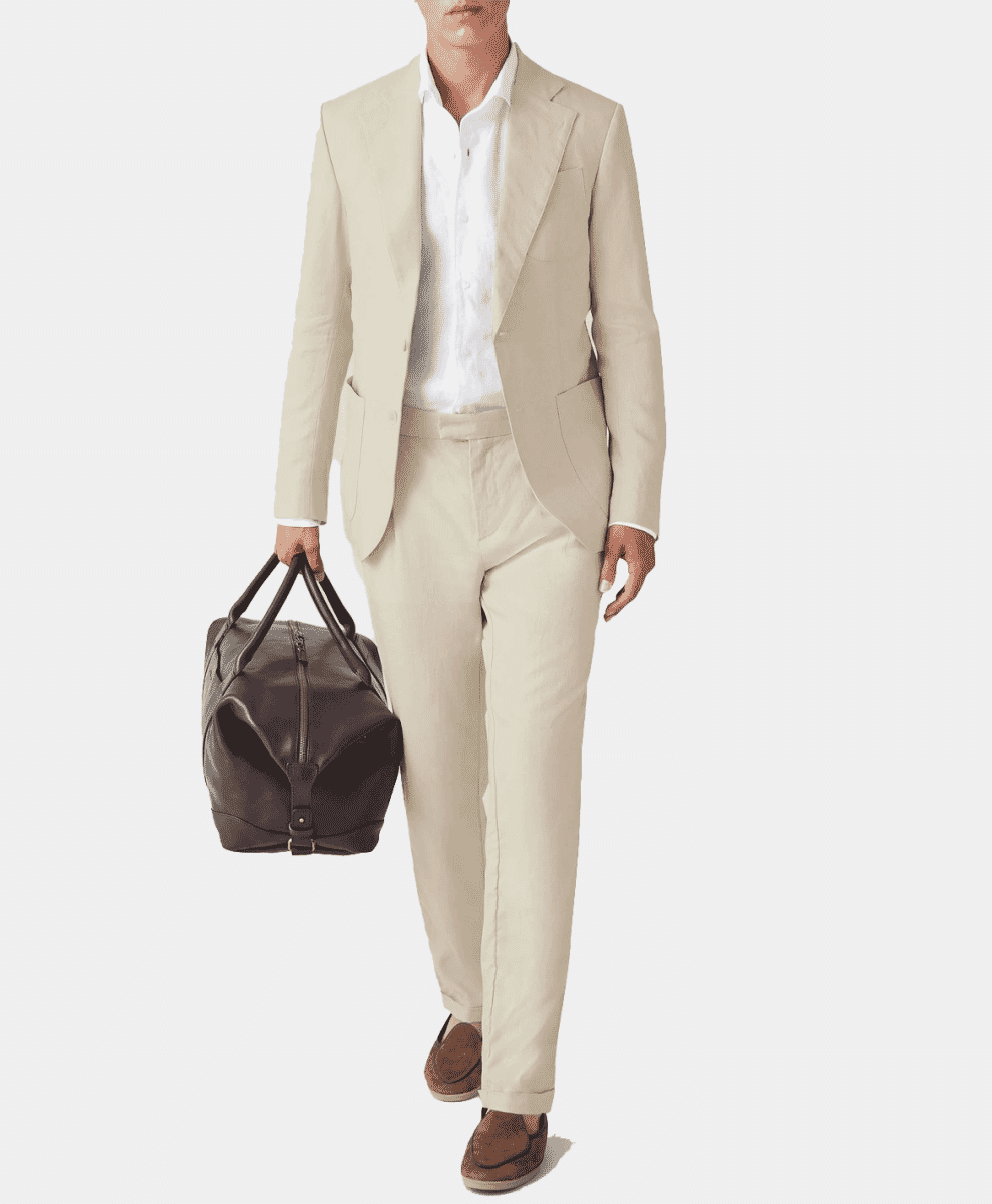 Man in a light beige linen suit carrying a dark leather duffel bag against a white background.