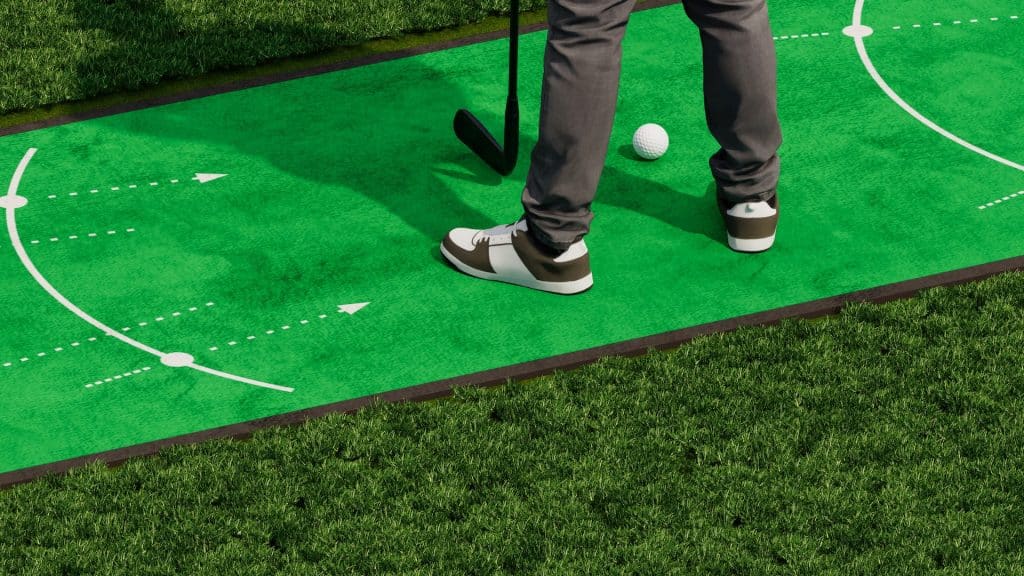 A golfer standing on a practice mat wearing white and brown hybrid golf shoes.