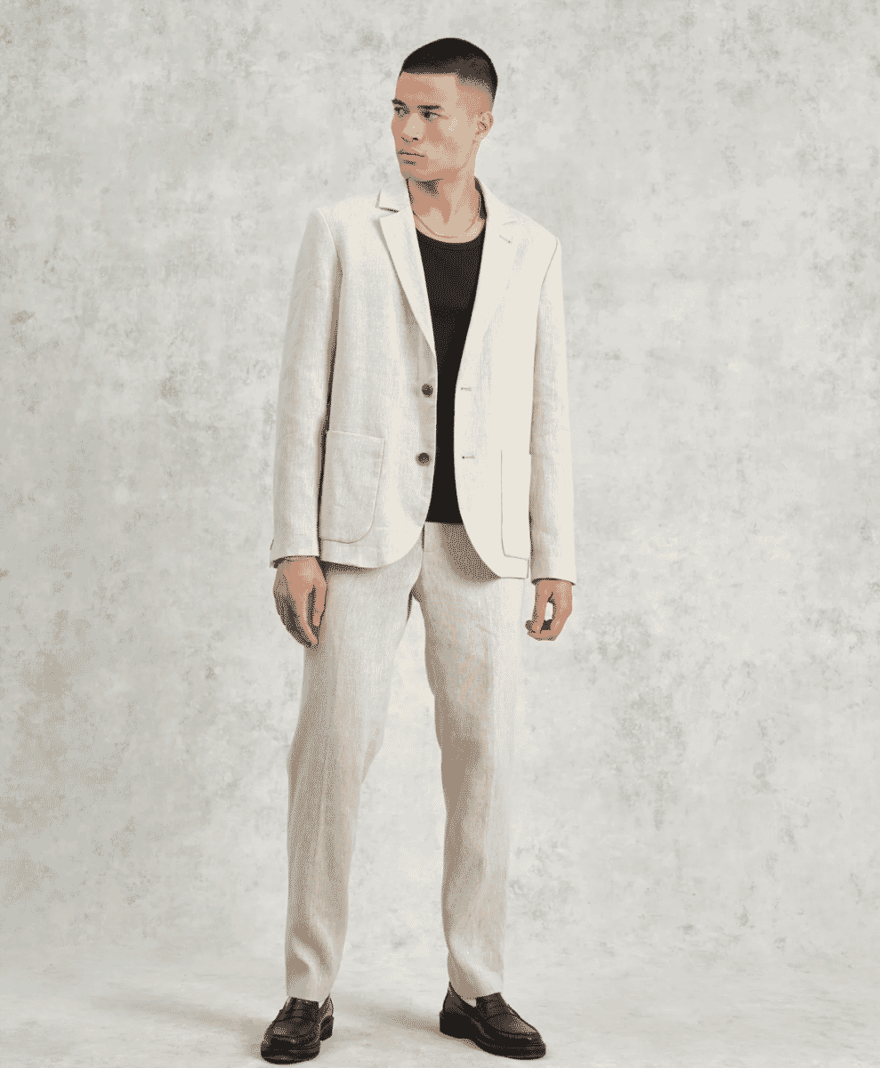 Man modeling a light-colored linen blazer over a black t-shirt and matching trousers.