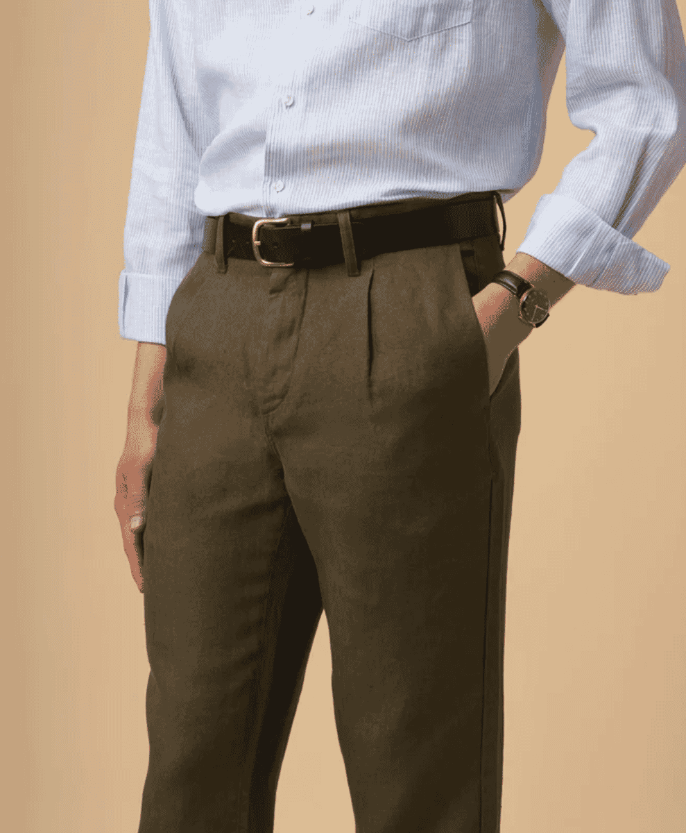 Man wearing olive-colored pleated trousers with a black belt and striped shirt.