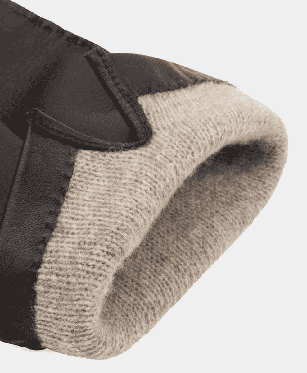 Close-up of a black leather glove with a cozy cream-colored knitted lining.