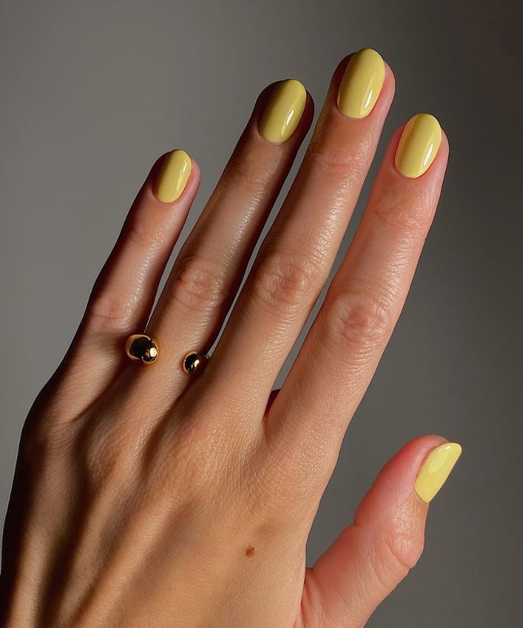 Butter yellow manicure on short, neatly manicured nails.