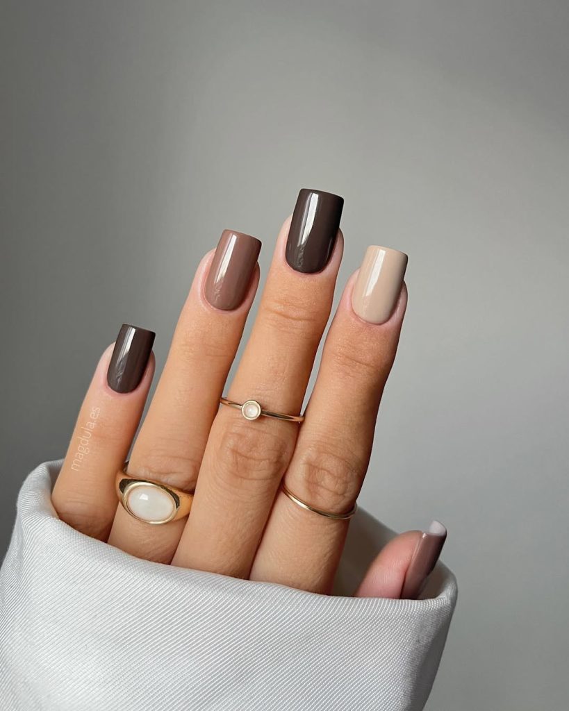 Minimalist neutral-toned manicure with gold rings and a white ribbed sleeve.