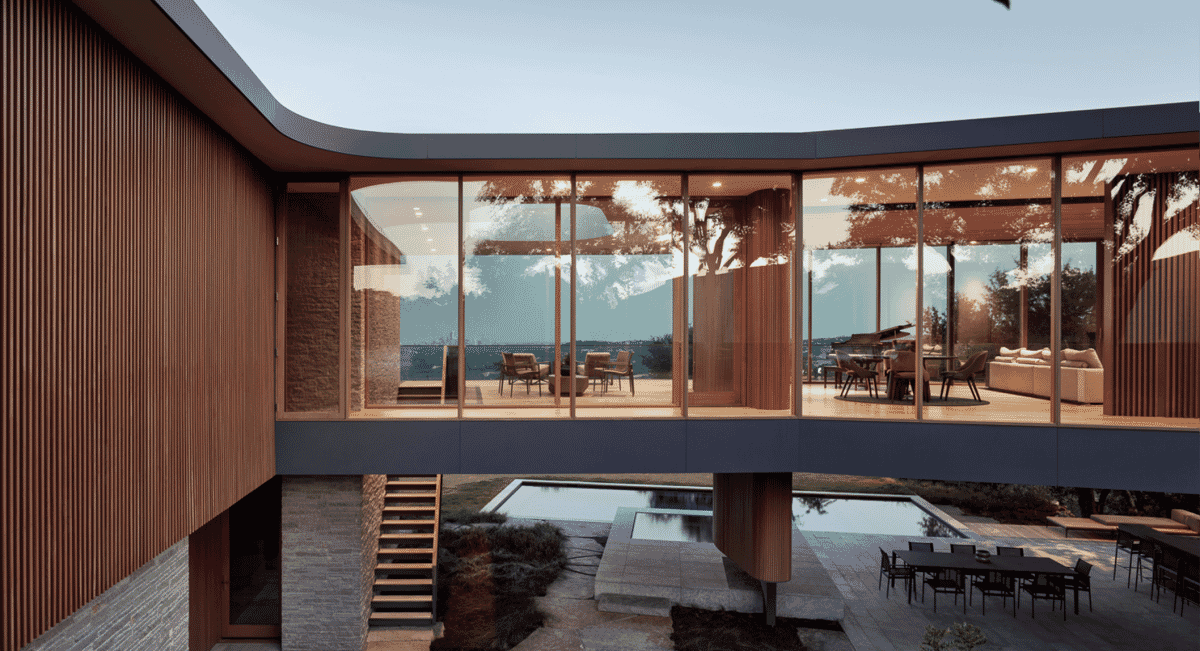 Indoor-outdoor living space with glass walls overlooking a pool and hills.