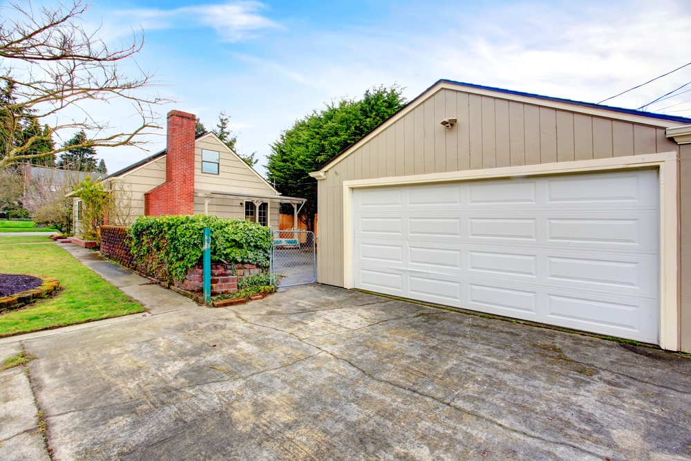 Exterior view of a residential garage with a white door and brick chimney.