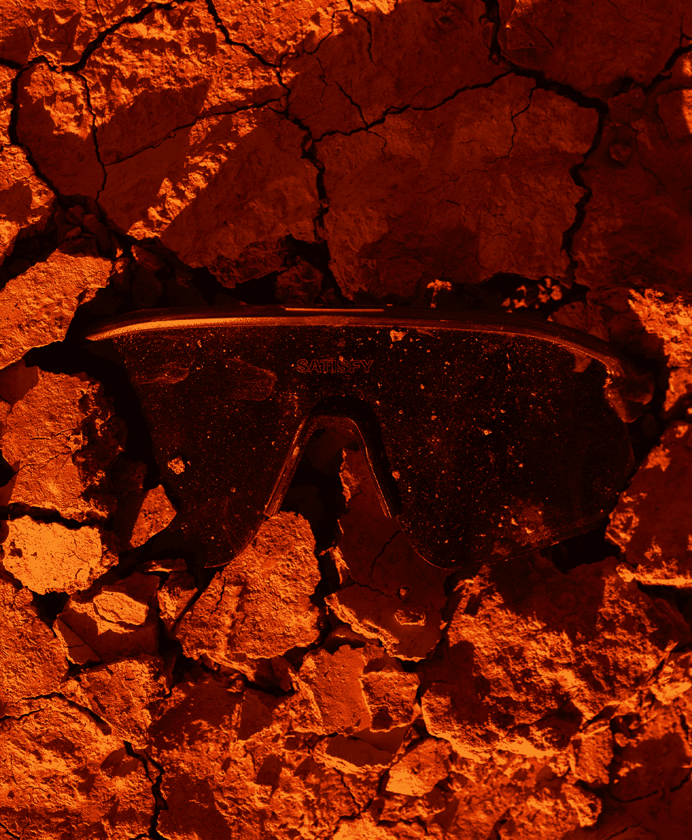 Black cycling goggles resting on cracked, sun-baked earth.