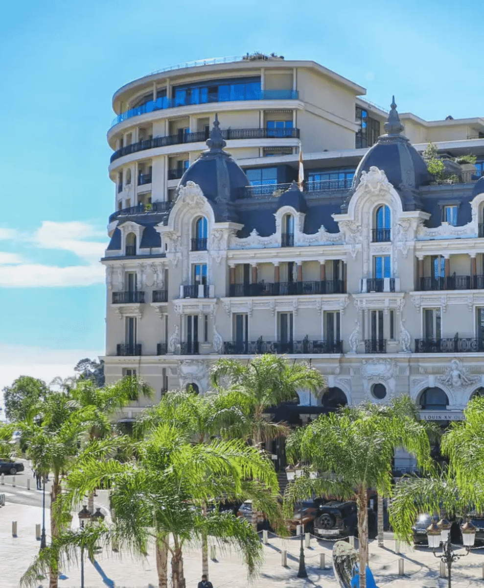 An ornate European building with blue domes and balconies framed by palm trees.