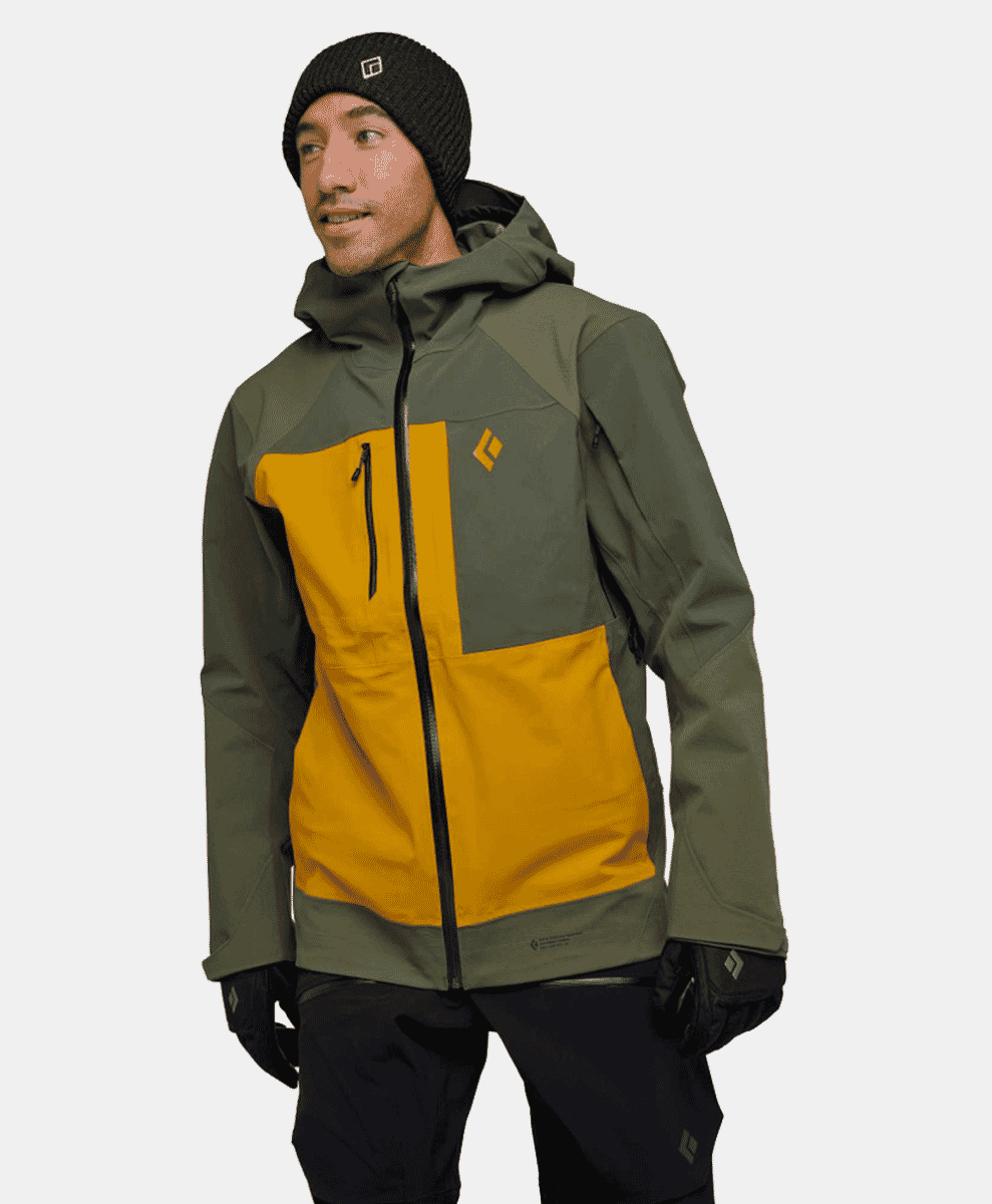 A model wearing a color-blocked olive and mustard yellow technical ski jacket.