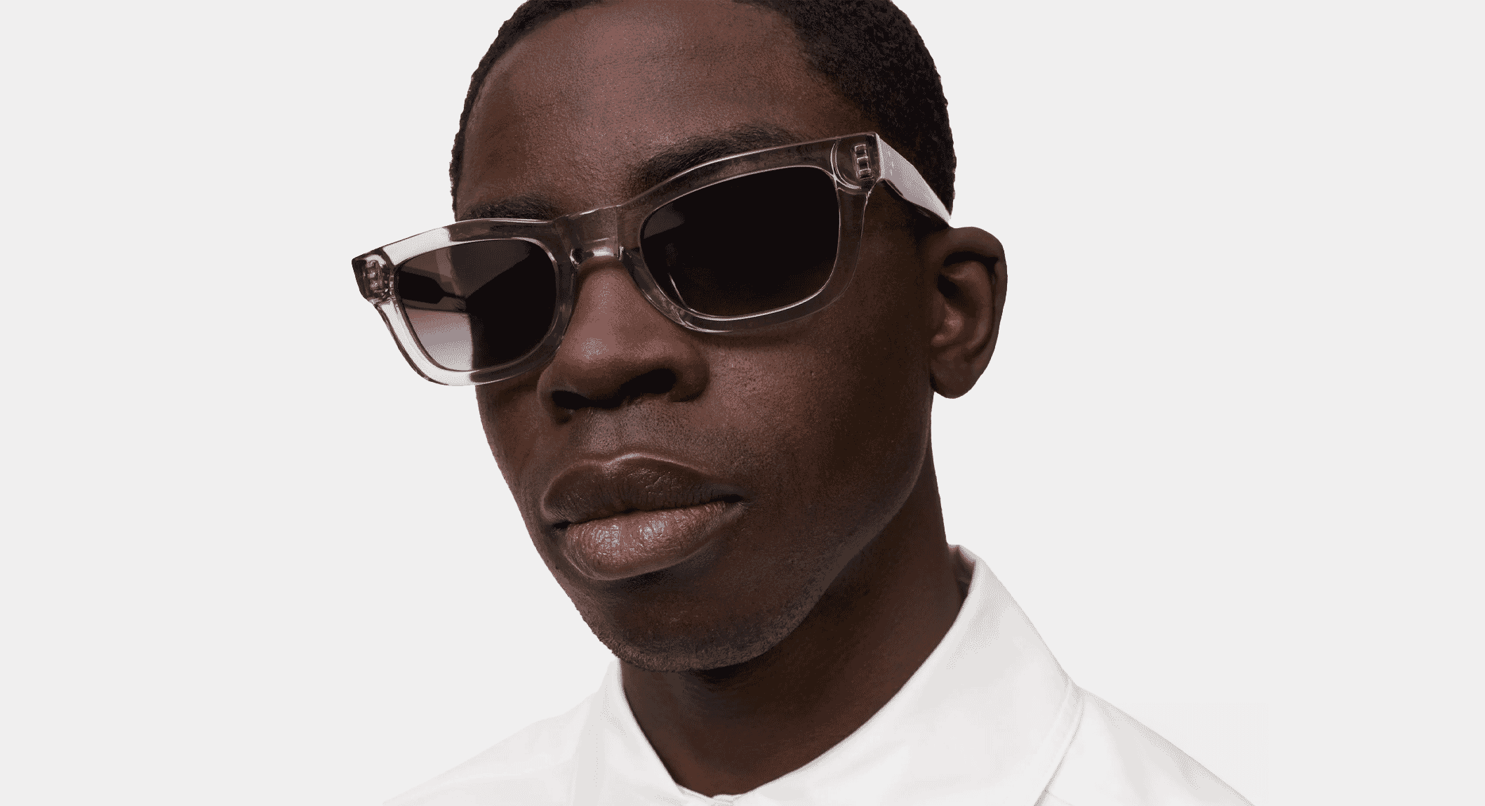 Urban-chic studio shot of a man wearing crystalline frames and a white shirt.