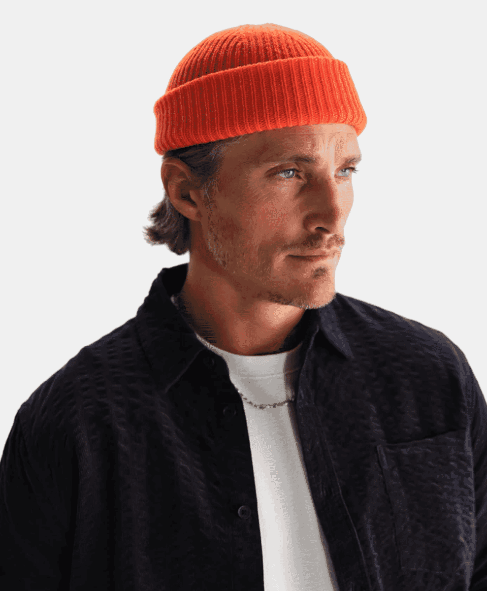 A man wearing an orange beanie and a textured dark shirt.