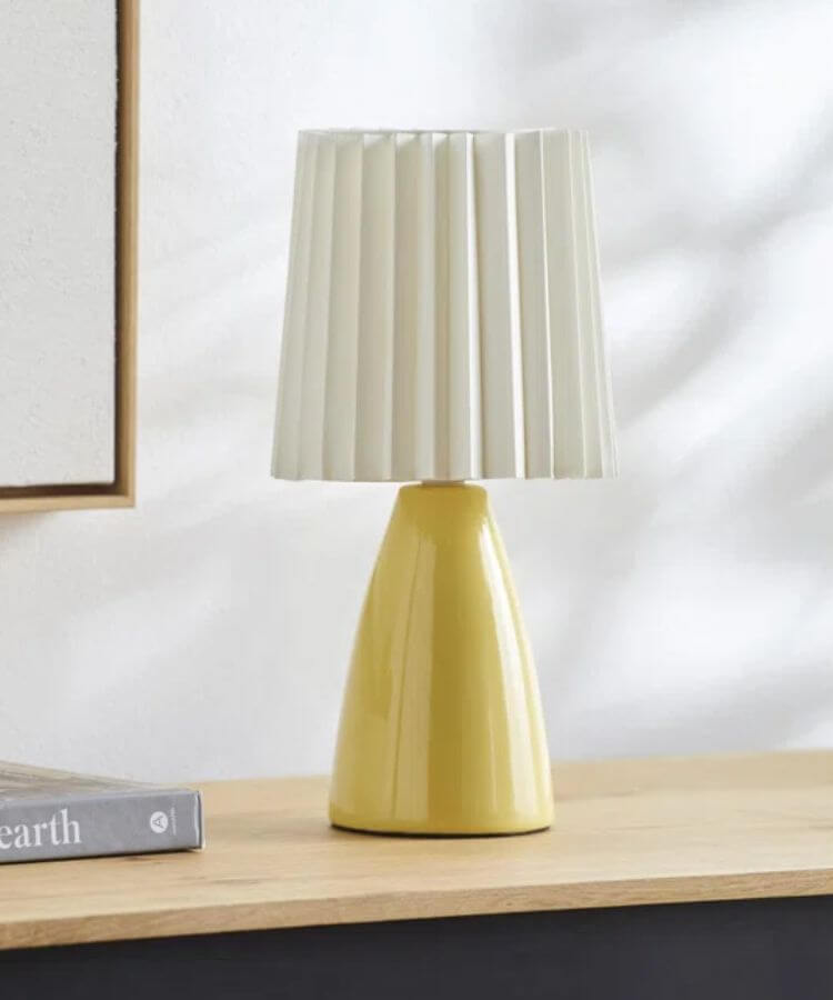 Small table lamp with a pleated yellow fabric shade.
