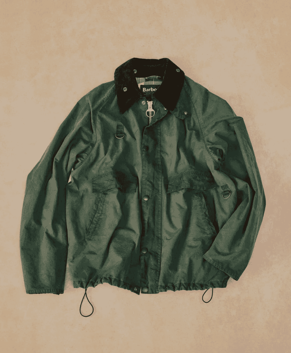 Flat lay of a green jacket highlighting the functional drawstring hem and utility pockets.