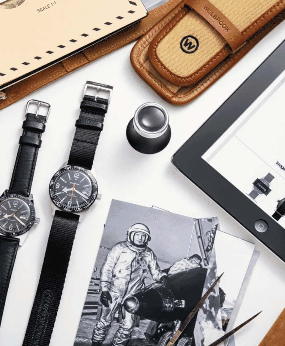 Flat-lay featuring vintage astronaut photography and two Wolbrook wristwatches.