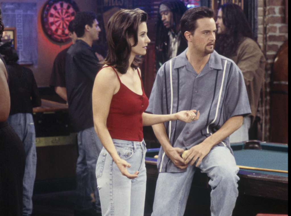 Monica Geller in a red tank top and high-waisted blue jeans.