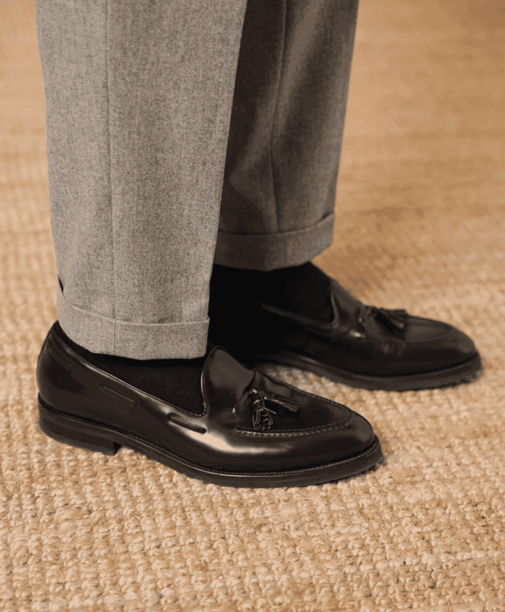 Close-up of grey cuffed wool trousers and black leather tassel loafers.