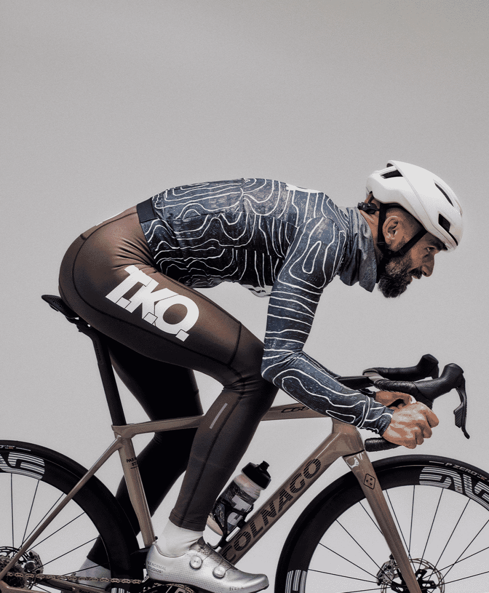 Detail of a cyclist on a Colnago bike wearing black-and-white TKO branded leggings.