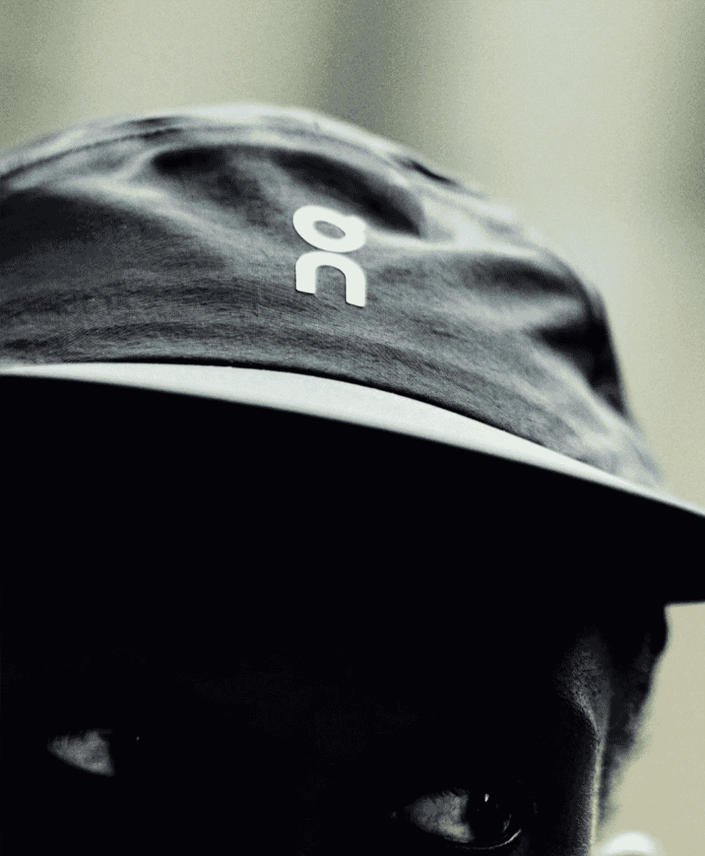 Monochrome shot of a person wearing a cap with a white 'ON' logo.