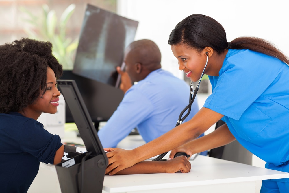 A wide shot of medical staff in professional attire working in a bright, modern clinical environment.