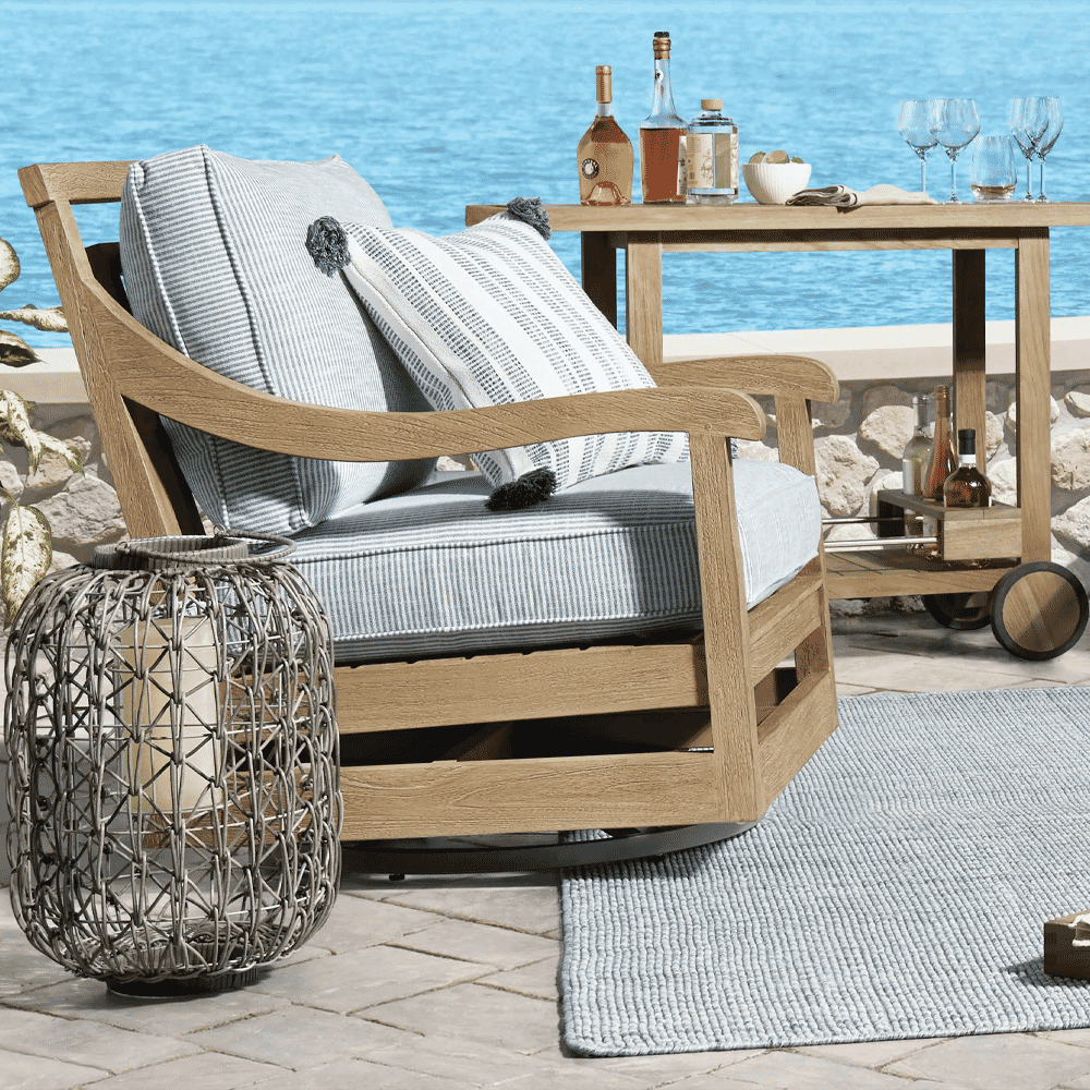 Outdoor patio scene with a wooden swivel chair, striped cushions, and a bar cart on stone flooring.