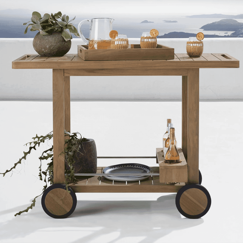 Detailed shot of a wooden outdoor bar cart with wicker accessories and wine bottles.