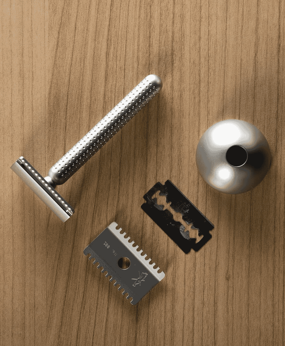 Close-up of a modern safety razor with a textured grip handle on a wooden surface.