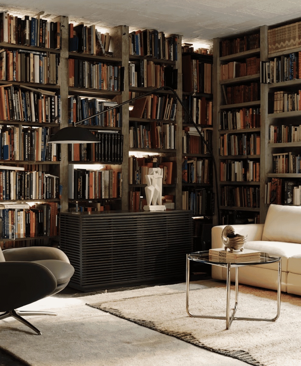 A cozy home library with wooden bookshelves and a black floor lamp creating a dedicated reading spot.