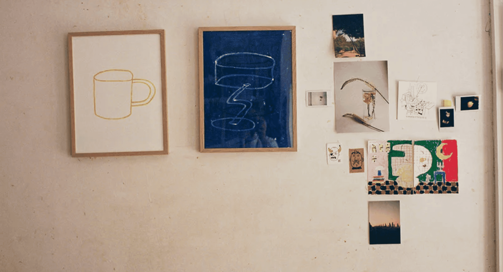 An eclectic gallery wall with various framed abstract prints and line drawings on a textured white background.