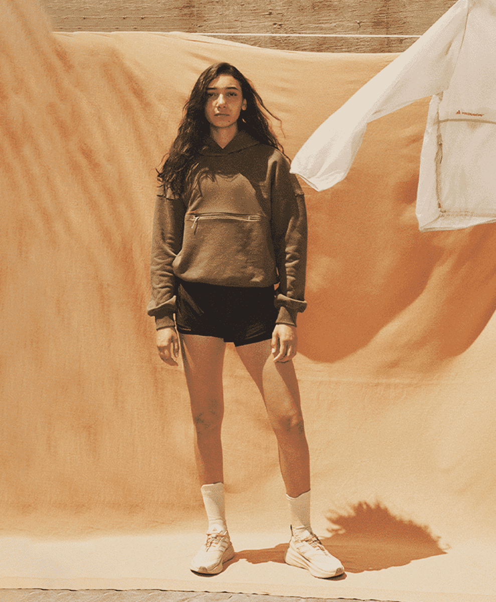 Woman wearing an oversized brown hoodie and Adidas running sneakers.