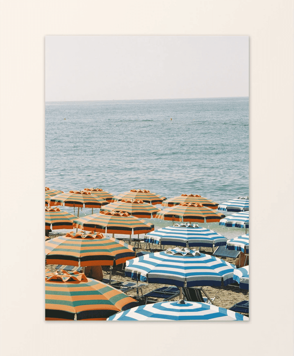 Colorful orange and teal striped beach umbrellas overlooking a calm blue sea.