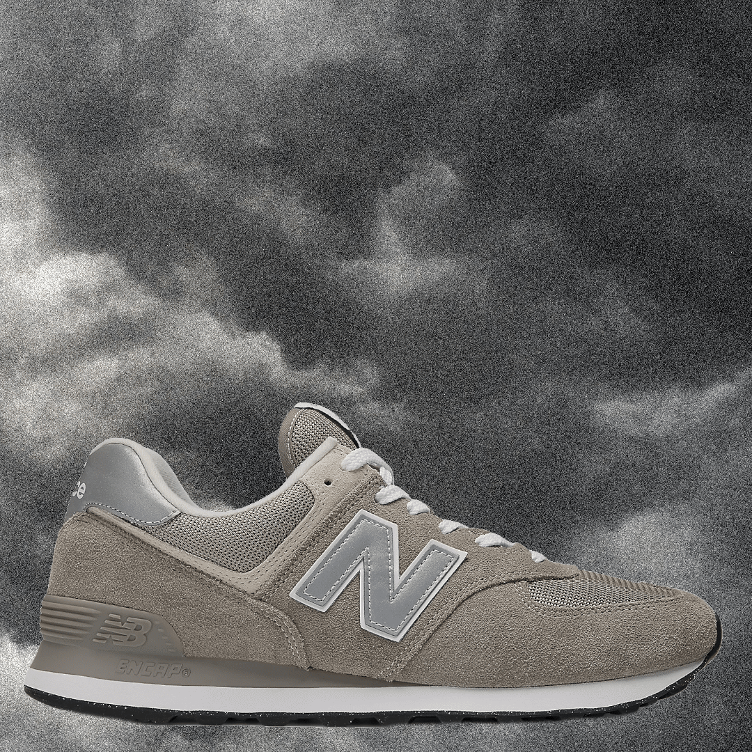 Classic beige New Balance 574 with a silver N logo against a cloudy sky background.