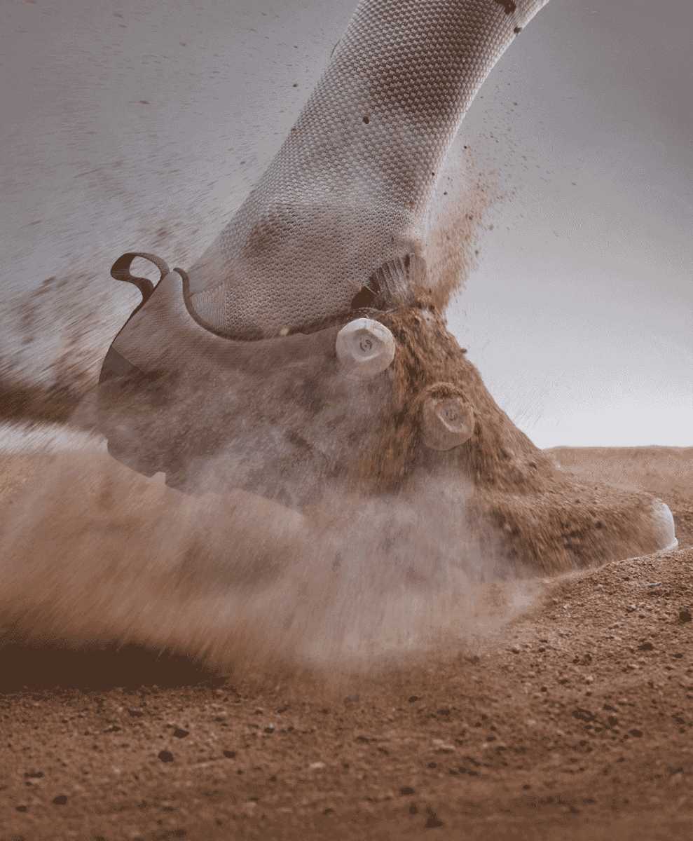 Cyclist's foot in a modern shoe kicking up a cloud of dust on a dirt trail.
