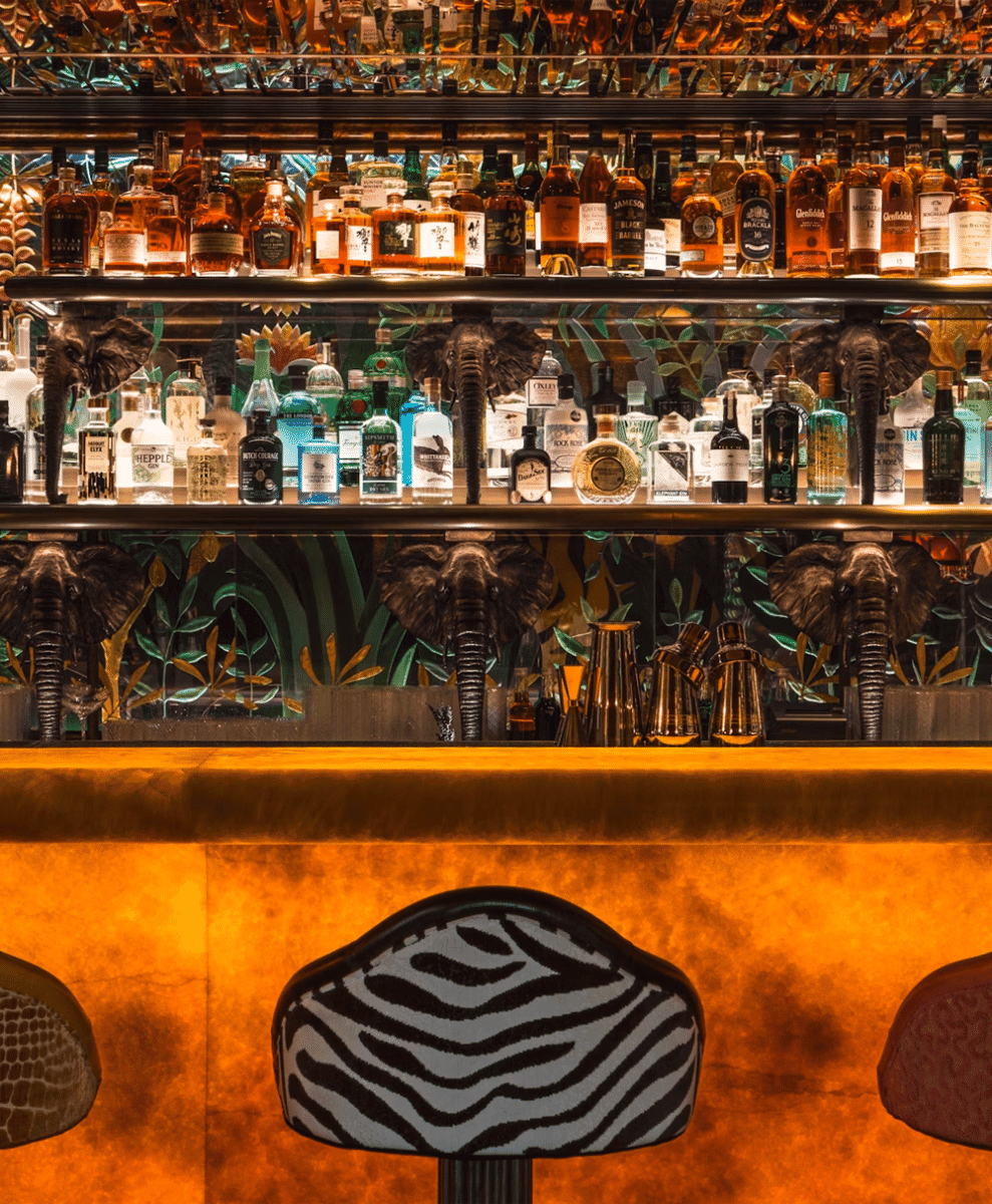 A luxury bar featuring zebra-print stools and elephant-themed decor under warm lighting.