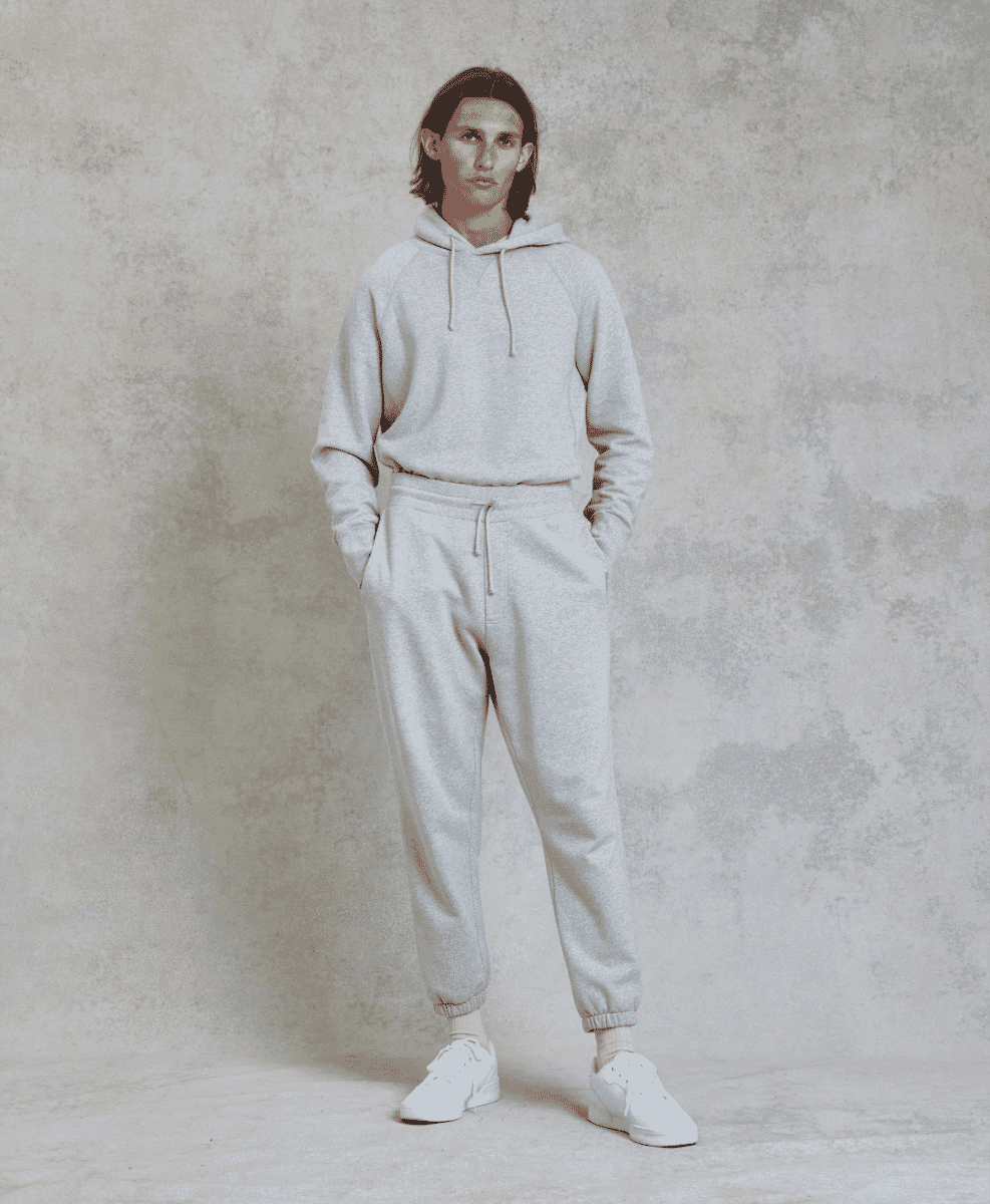 Man in a light gray hoodie and matching jogger set with white sneakers.