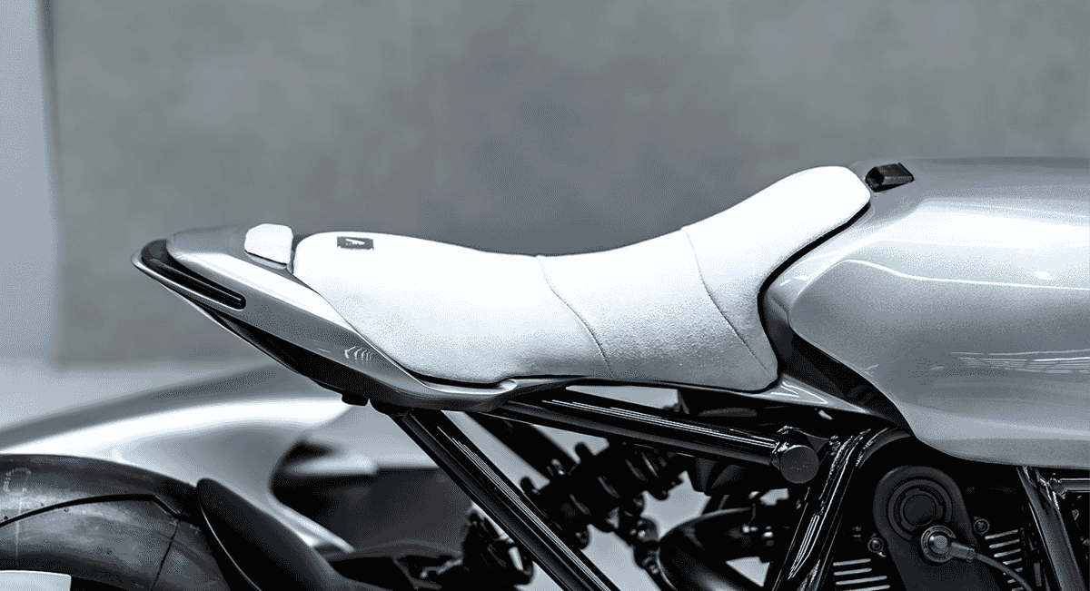 Close-up of a sleek white motorcycle seat cover meeting the polished chrome tail section.