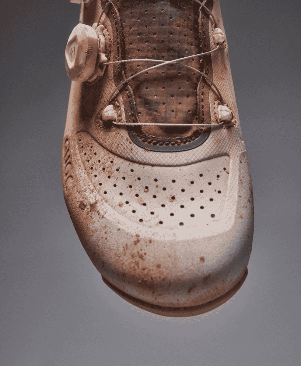 Close-up of a mud-splattered cycling shoe with a Boa dial closure.