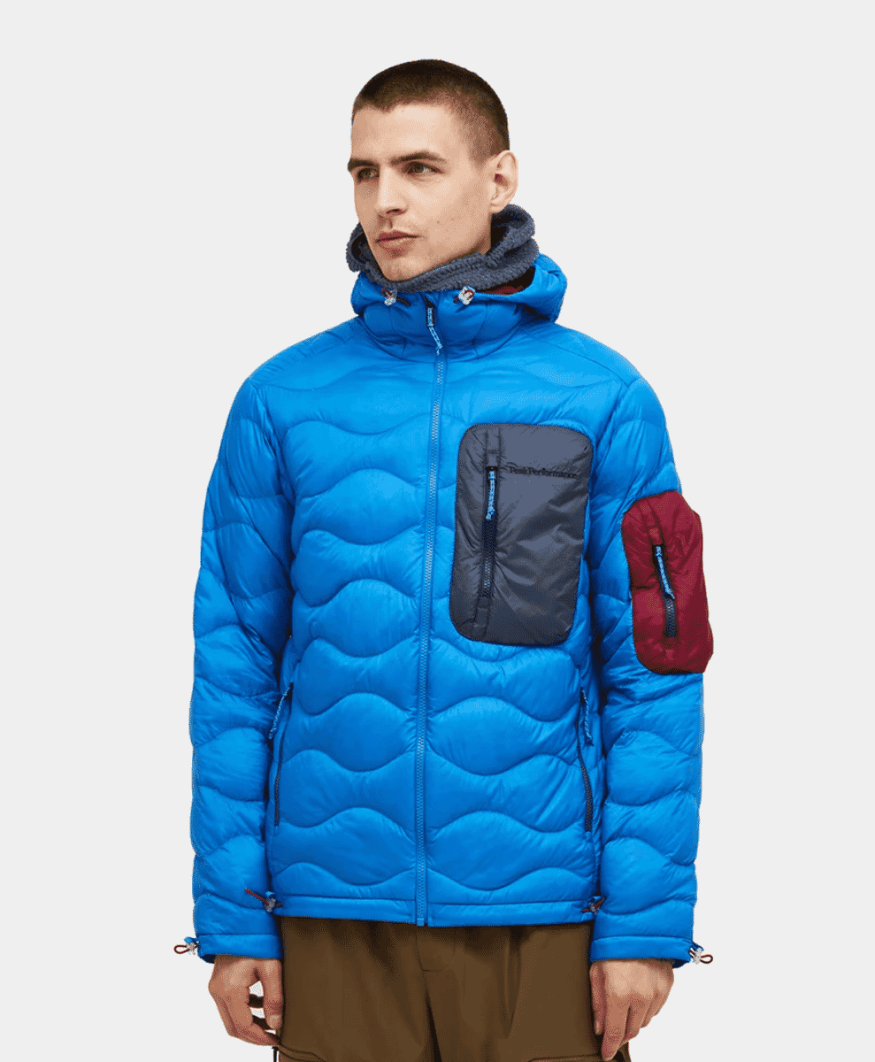 Close-up of a vibrant blue quilted down jacket with a gray chest pocket and red details.