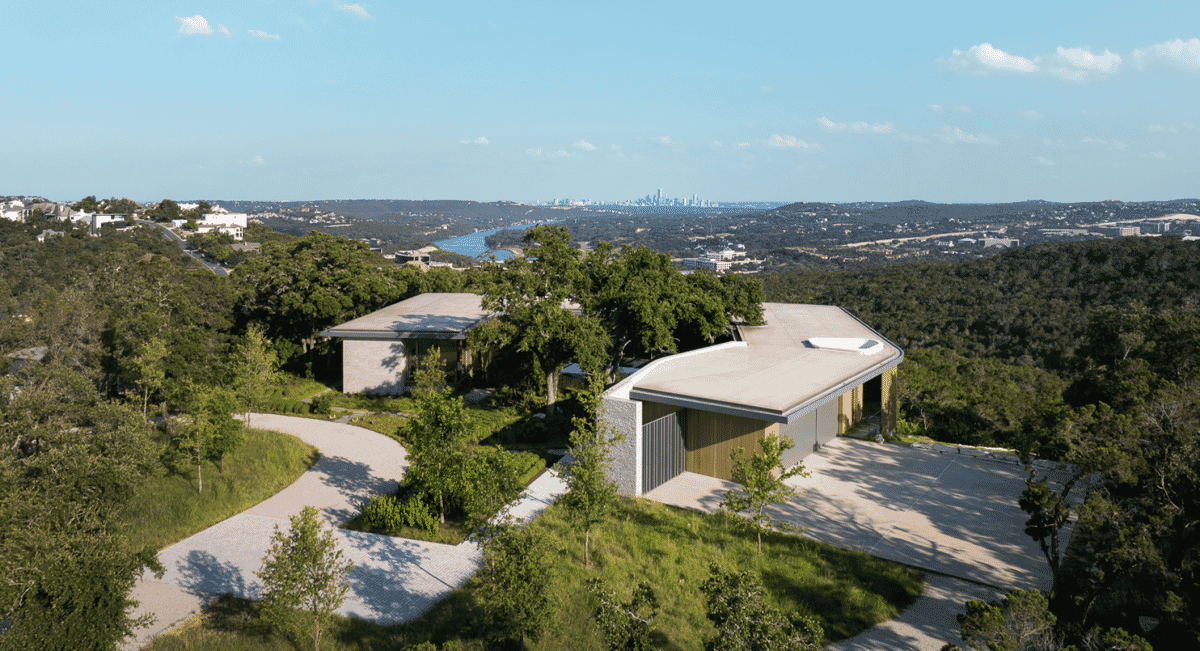Panoramic view of a modern architectural home on a hillside overlooking the city skyline.