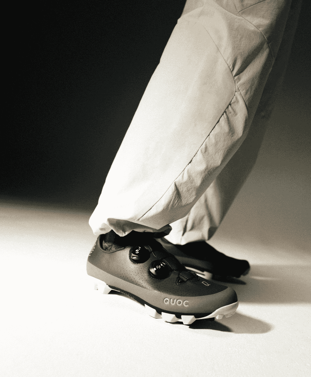 Studio shot of a cyclist wearing grey QUOC M3 Sport shoes with a BOA fit system and casual pants.