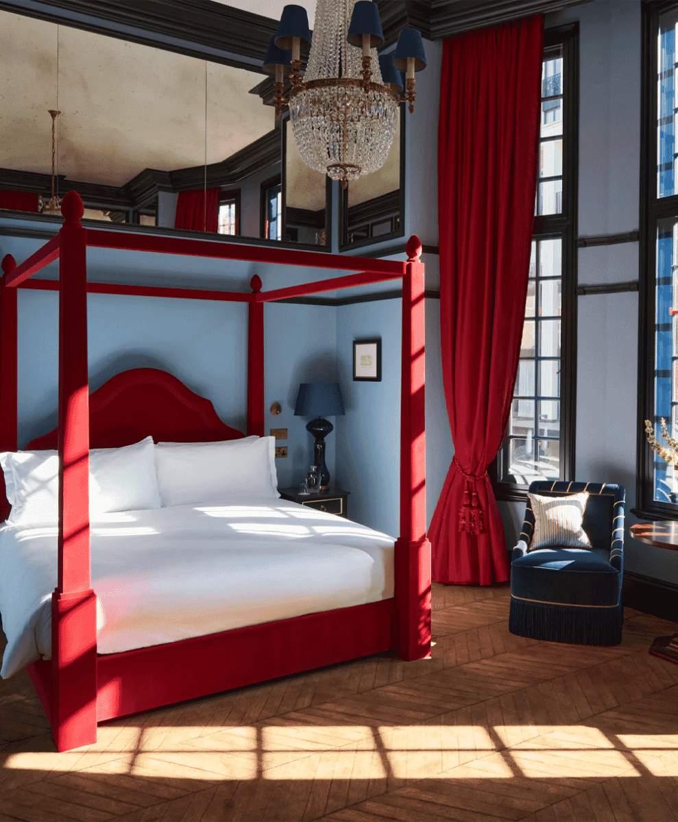 Luxurious bedroom with a bold red four-poster bed and deep blue walls.