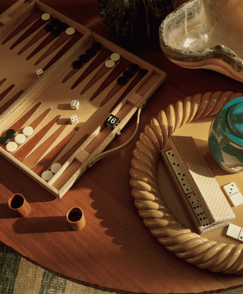 A warm-toned still life featuring a backgammon set and decor on a wooden table.